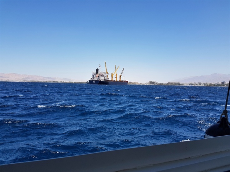 A ship sailing through the choppy waters of the Red Sea, just outside the port of Aqaba